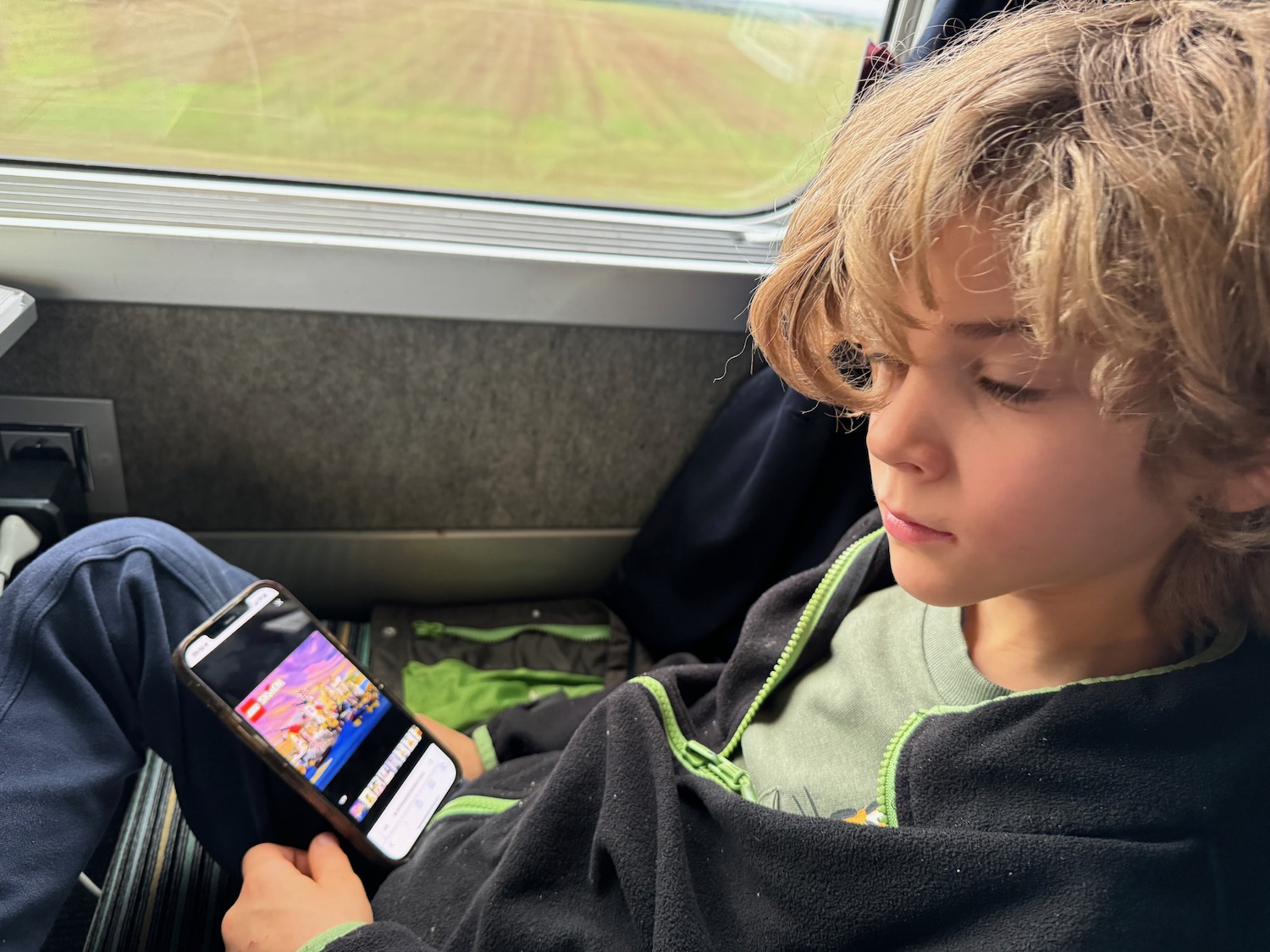 a boy sitting in a bus looking at a cell phone