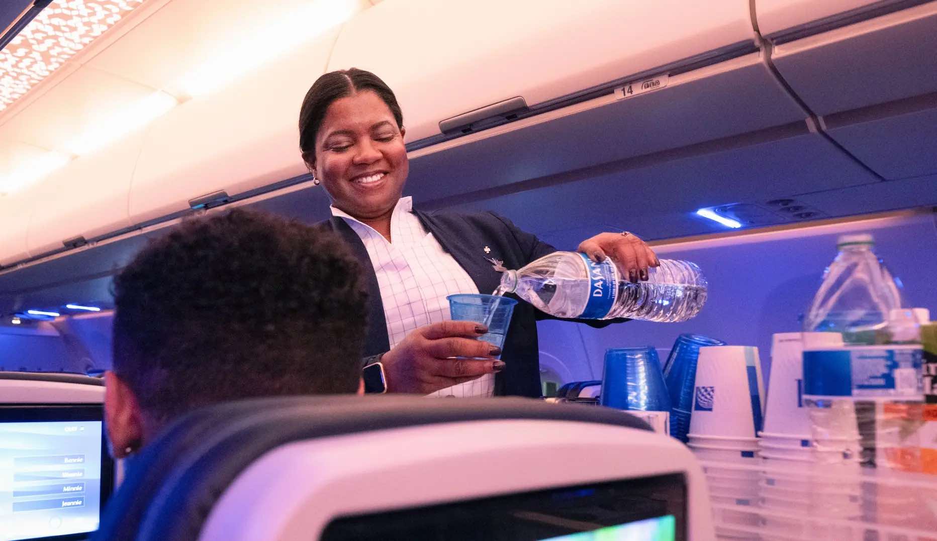 a woman pouring water into a plastic cup