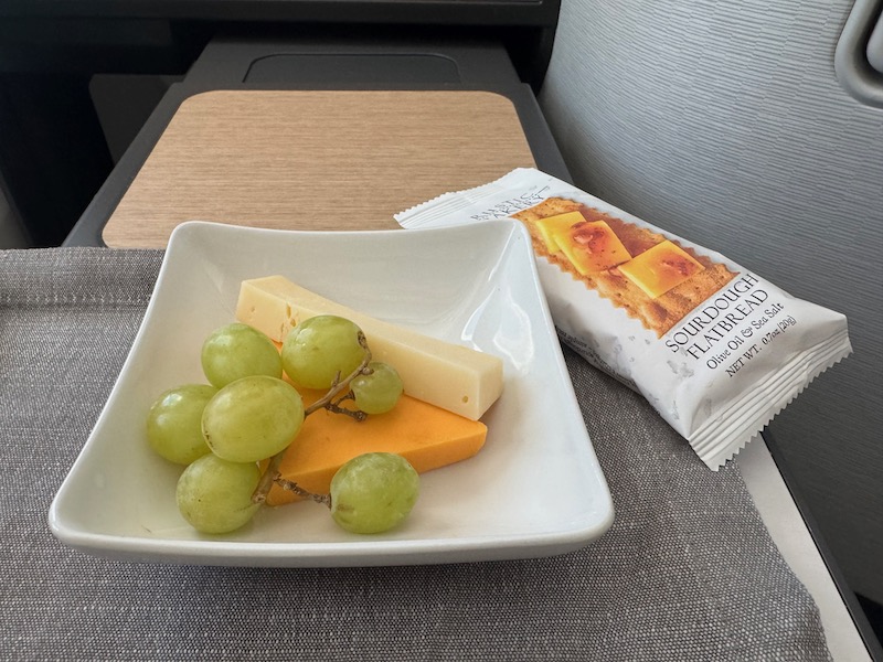 a plate of cheese grapes and a packet of food