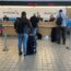 people standing in front of a desk with luggage