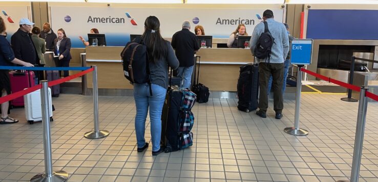 people standing in front of a desk with luggage
