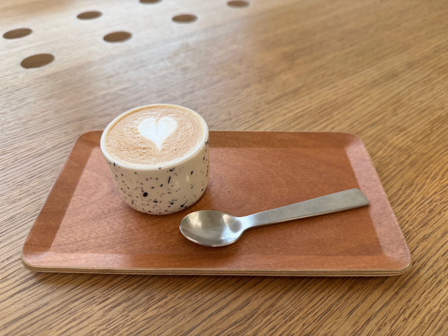 a cup of coffee with a heart on top of it and a spoon on a tray