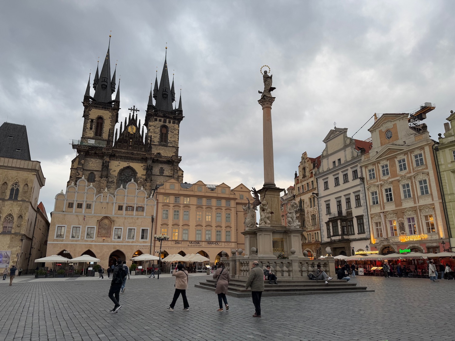 a group of people walking in a plaza with a statue in front of a building