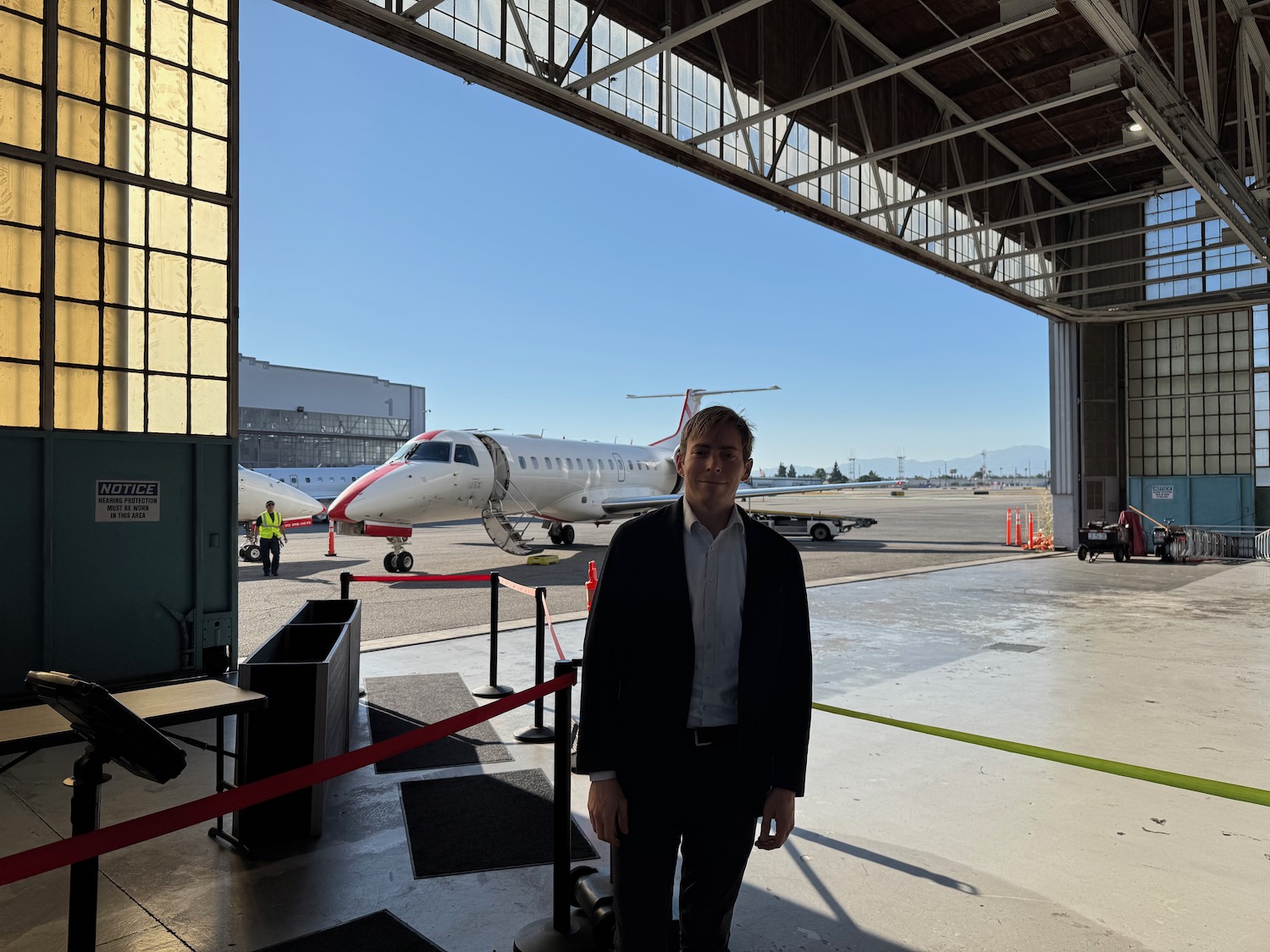 a man standing in a hangar with a plane in the background