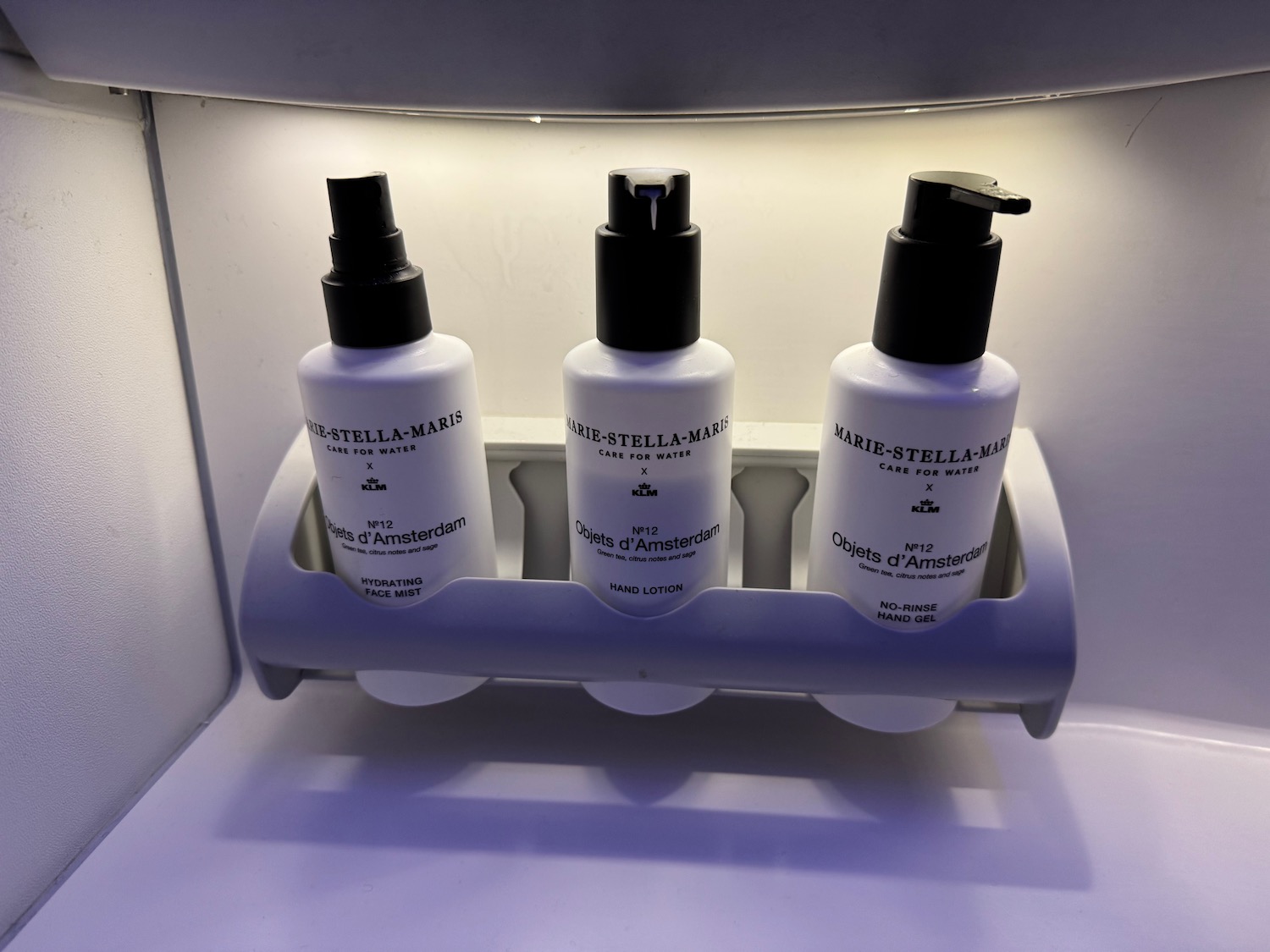 a group of white bottles with black caps on a white shelf
