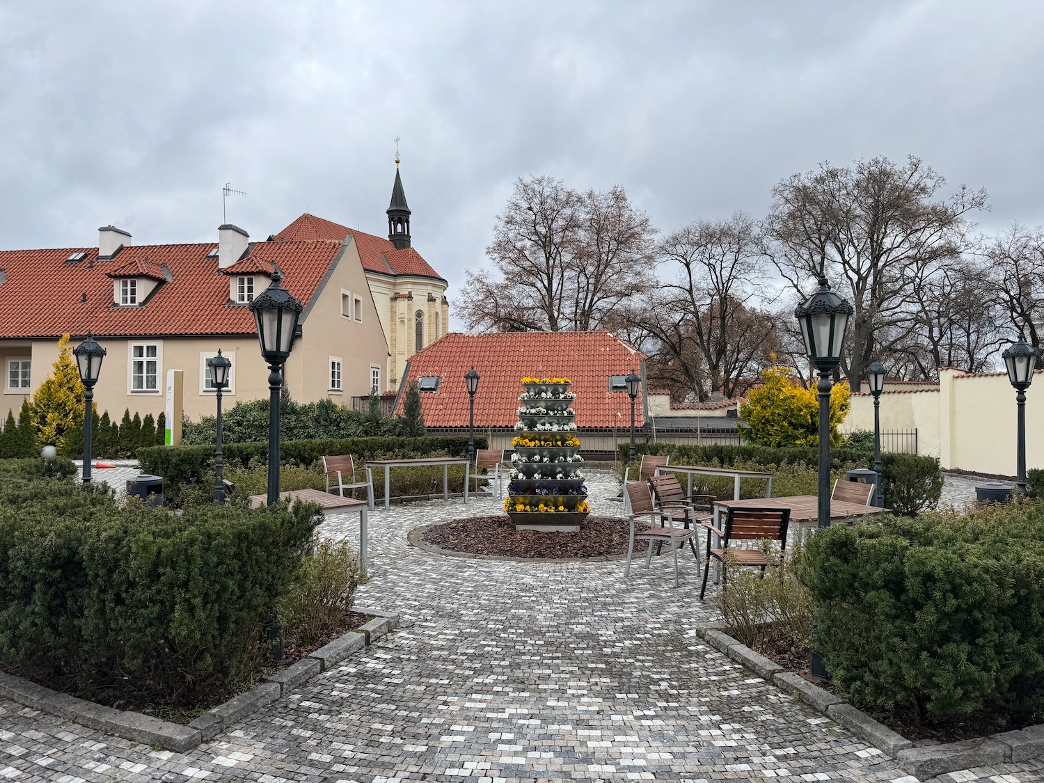a stone walkway with a fountain and trees and buildings
