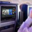 a man sitting in an airplane with a screen on