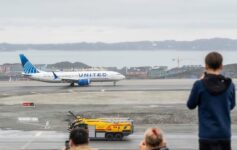 people looking at an airplane on a runway