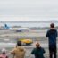 people looking at an airplane on a runway