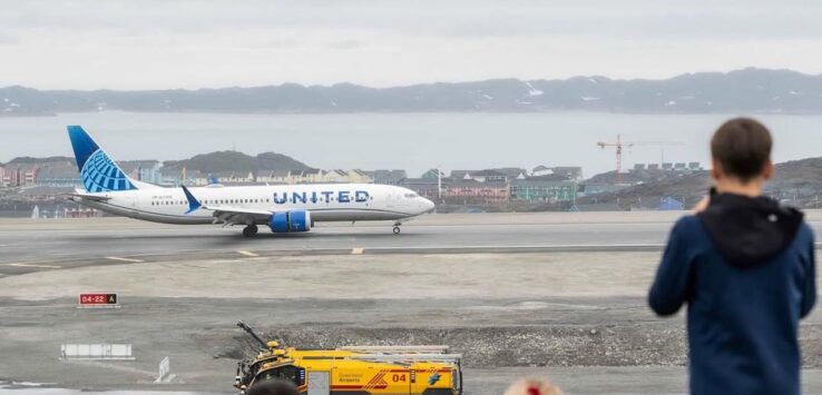 people looking at an airplane on a runway