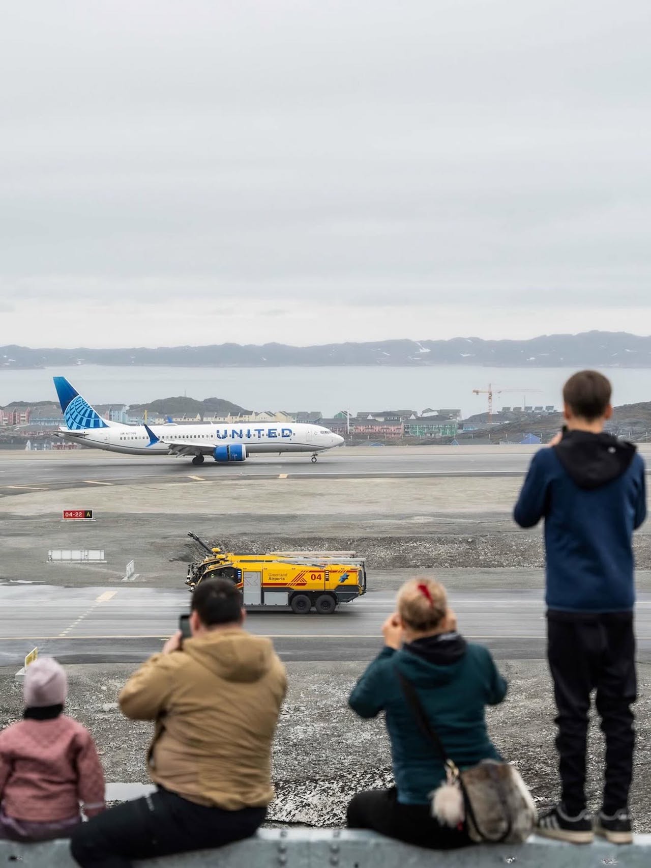 people looking at an airplane on a runway