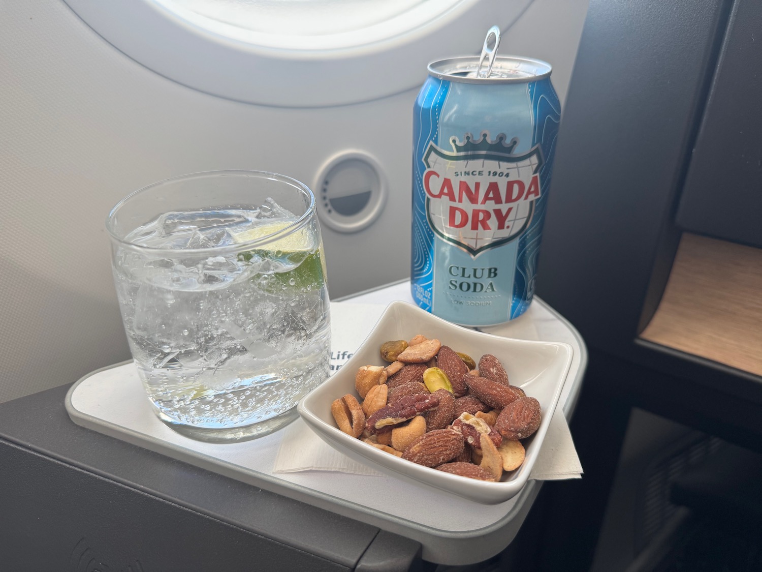 a can of soda and a bowl of nuts on a table