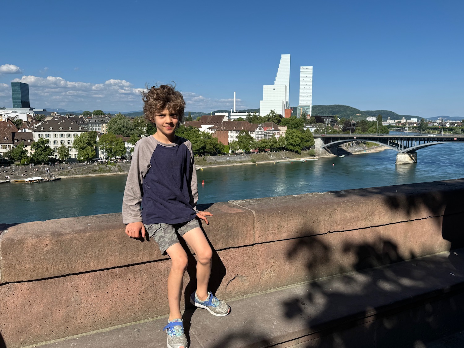 a boy sitting on a ledge by a river