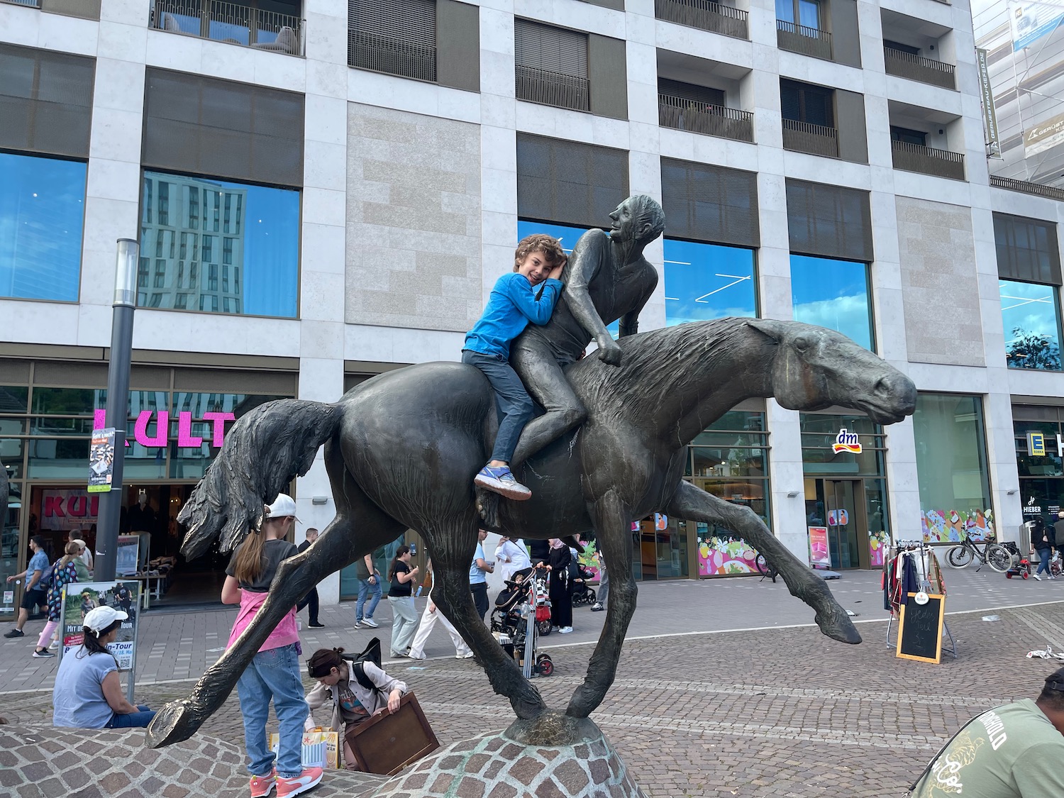 a boy riding a horse statue in front of a building