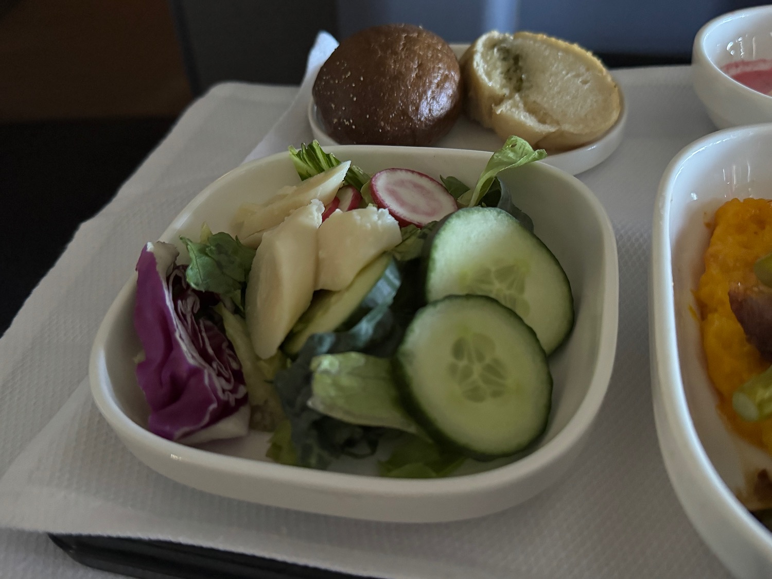 a bowl of salad and buns on a tray