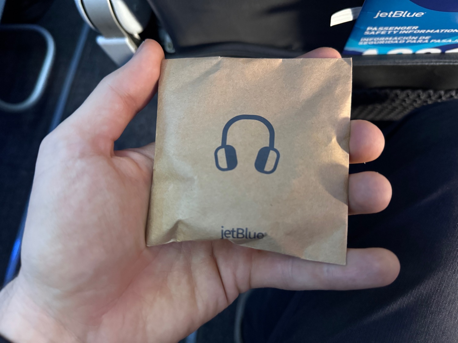 a hand holding a brown paper bag with headphones on it