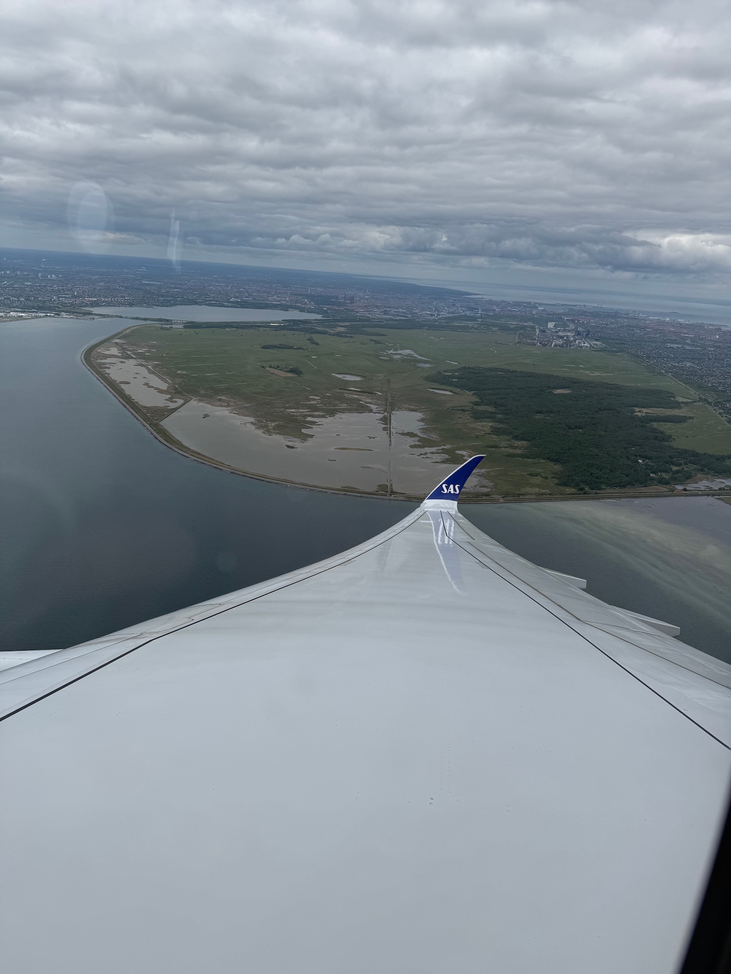 an airplane wing with land and water in the background