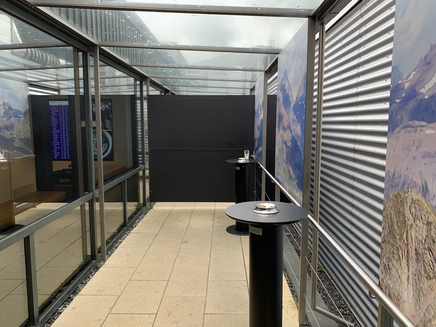 a glass covered walkway with a table and a poster on the wall