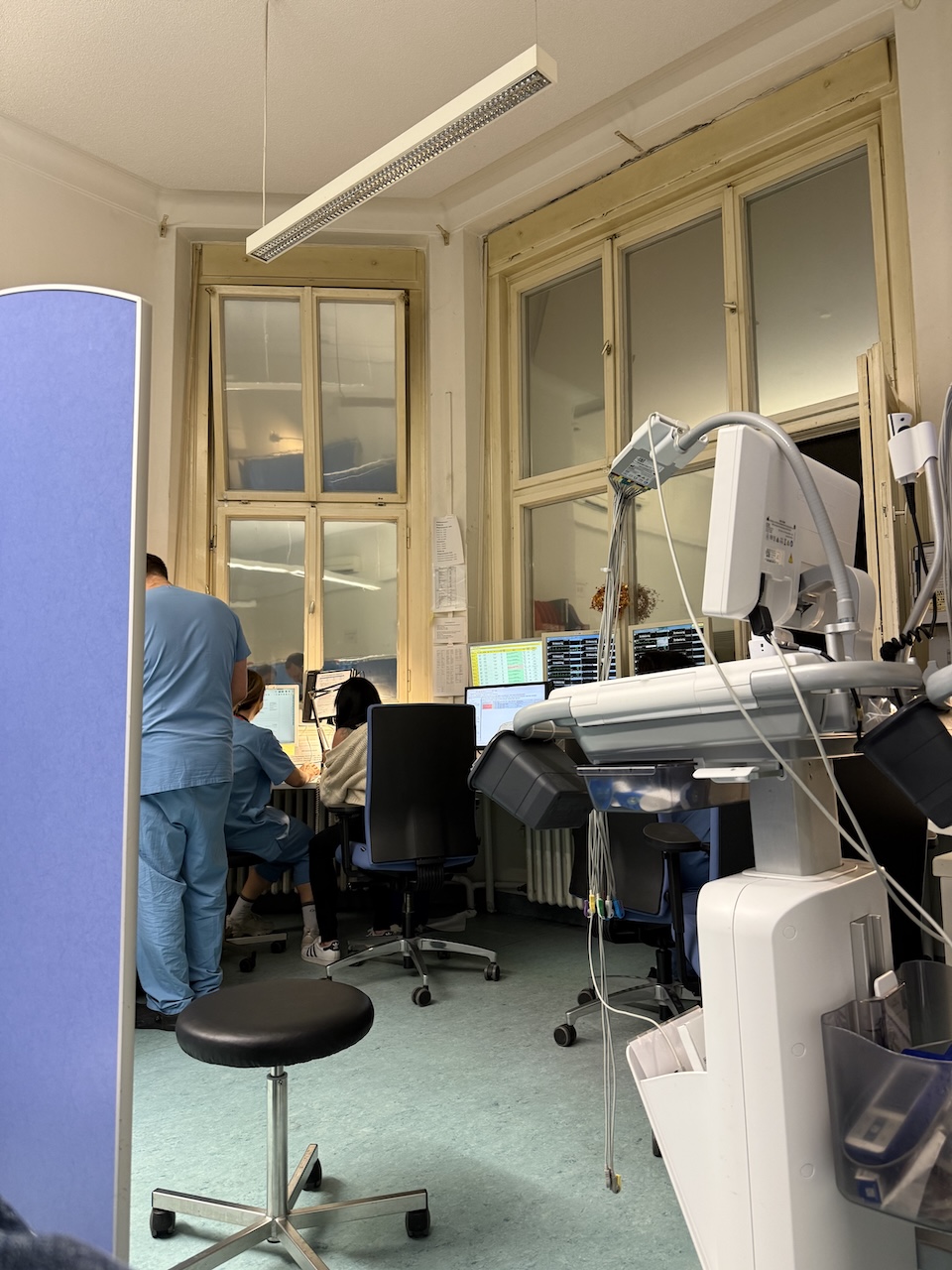 a room with a few people in blue scrubs and a computer