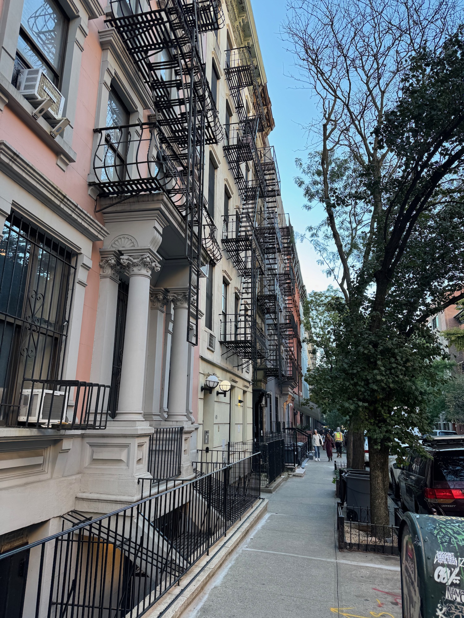 a sidewalk with a row of buildings and a tree