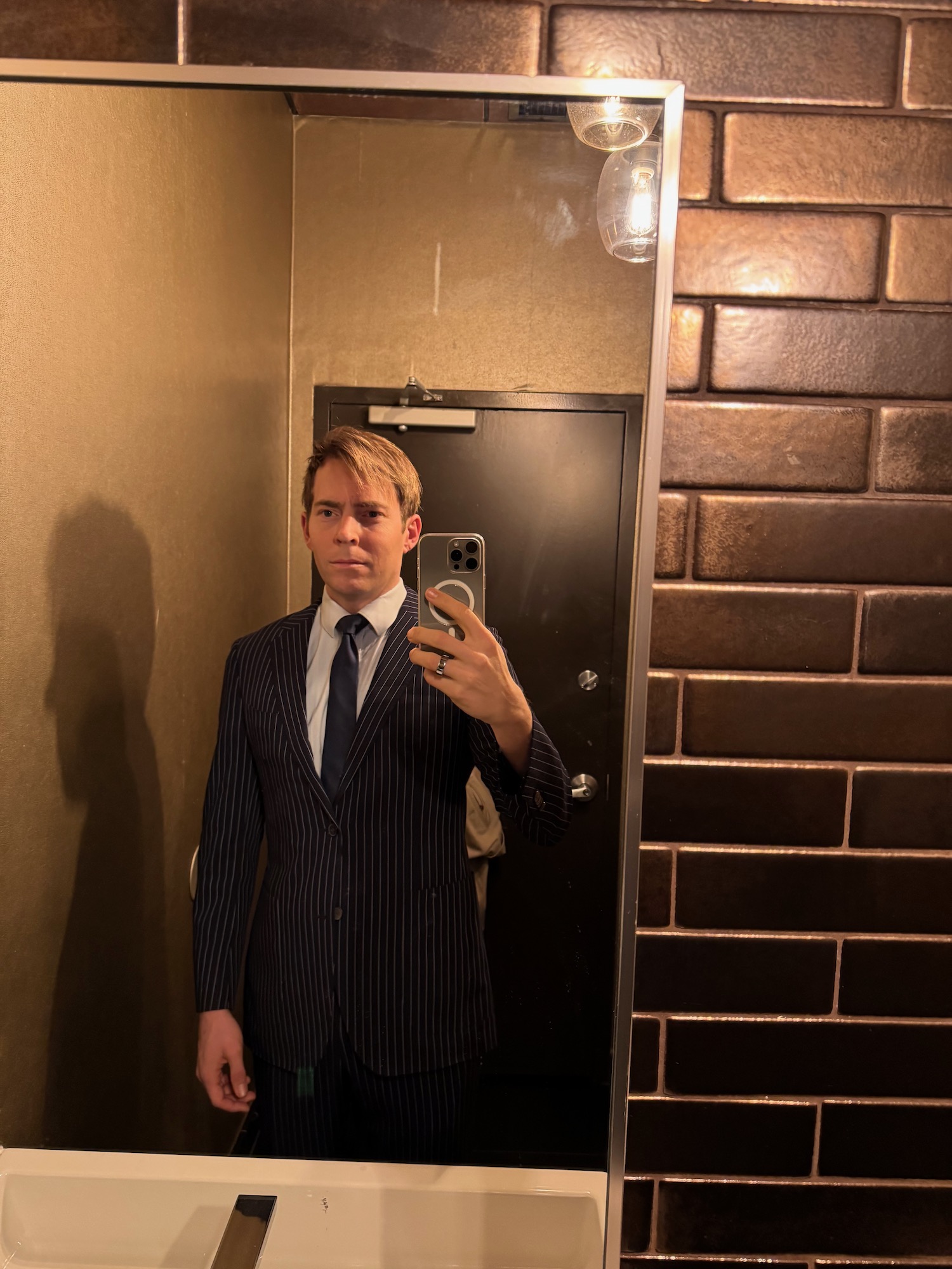 a man in a suit taking a selfie in a mirror