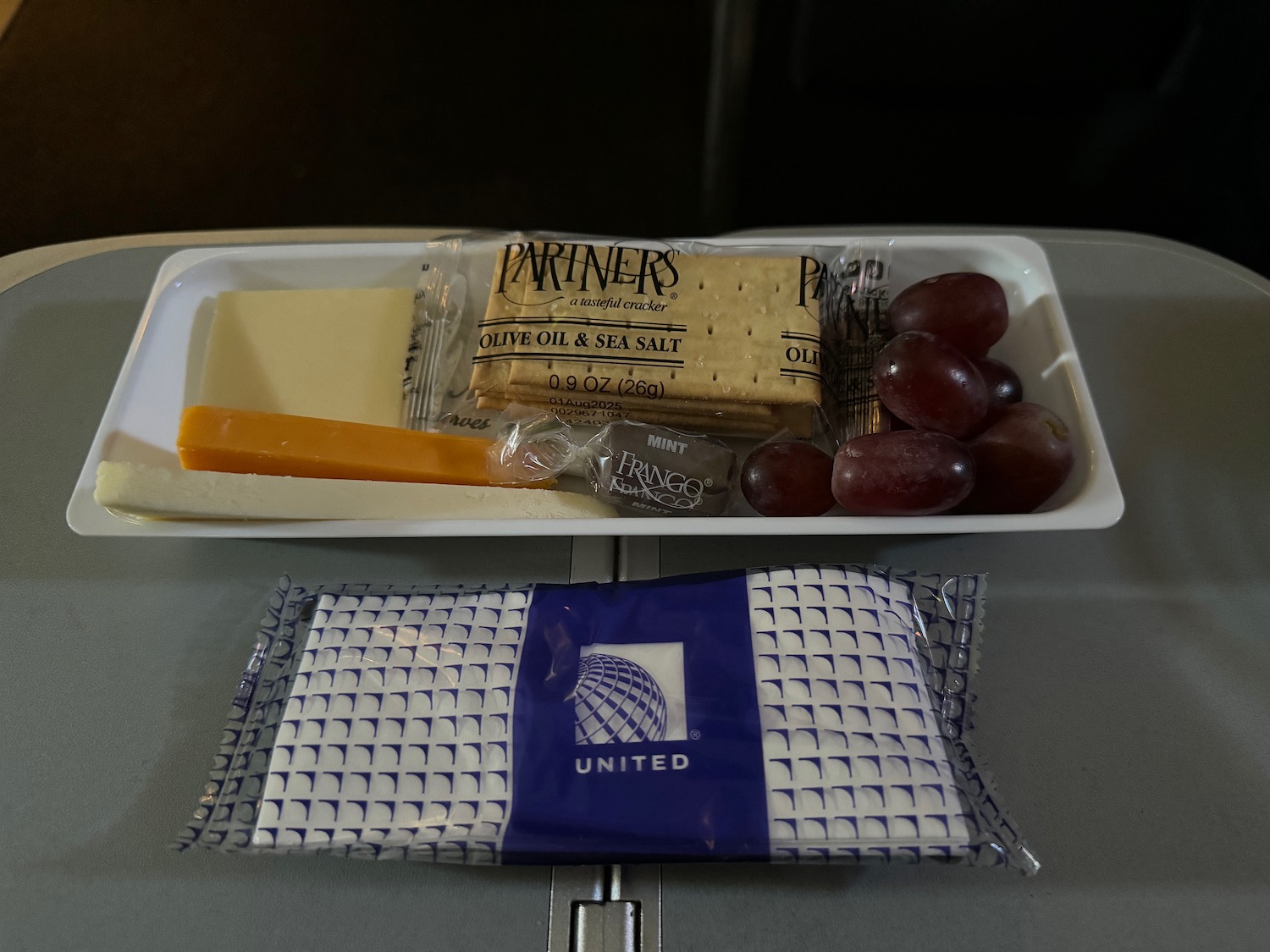 a tray of food and a package of cheese and grapes