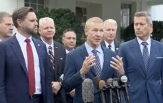 a group of men in suits standing in front of microphones
