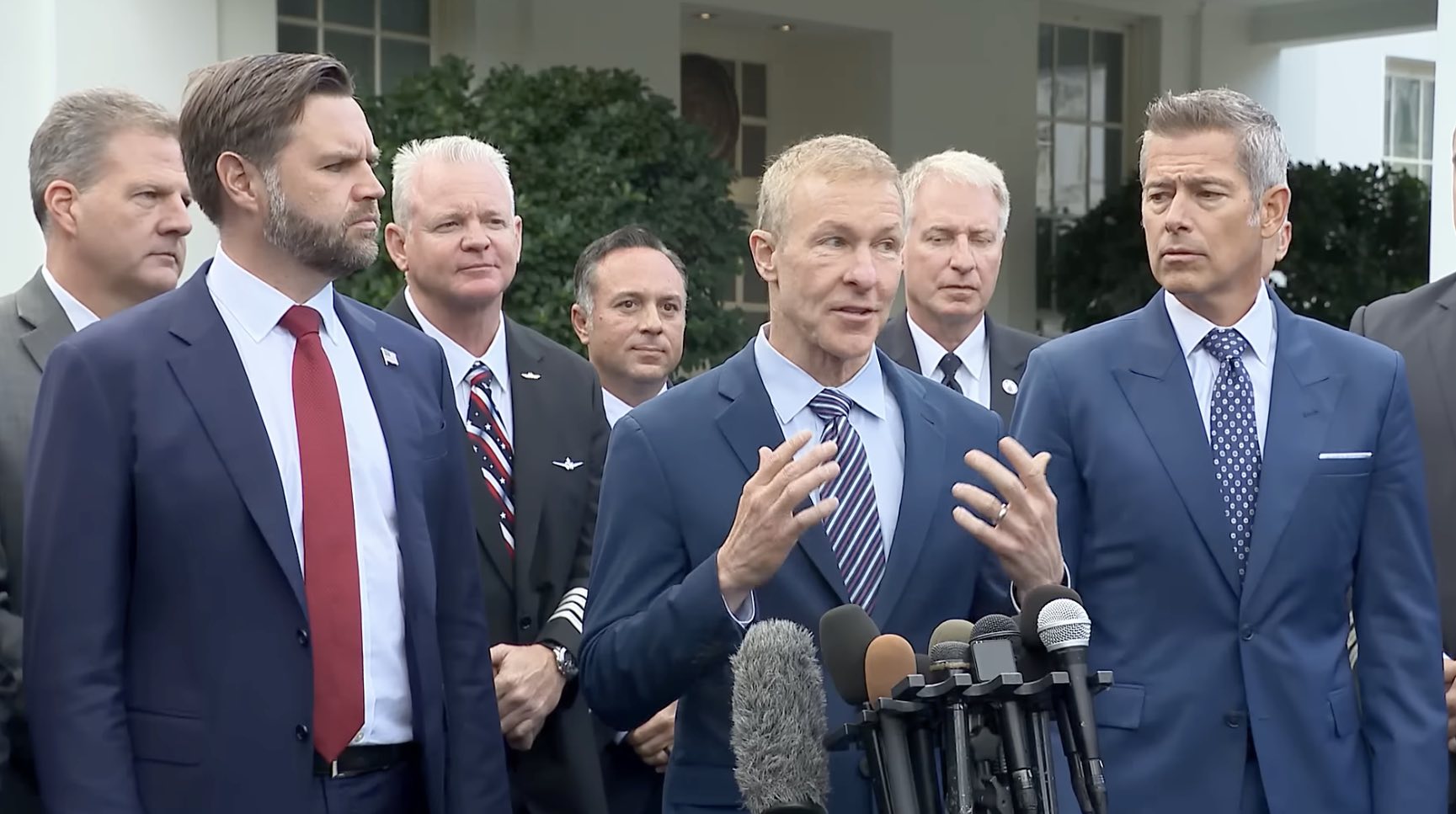 a group of men in suits standing in front of microphones