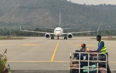 a group of people sitting on a runway with a large white airplane