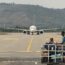 a group of people sitting on a runway with a large white airplane