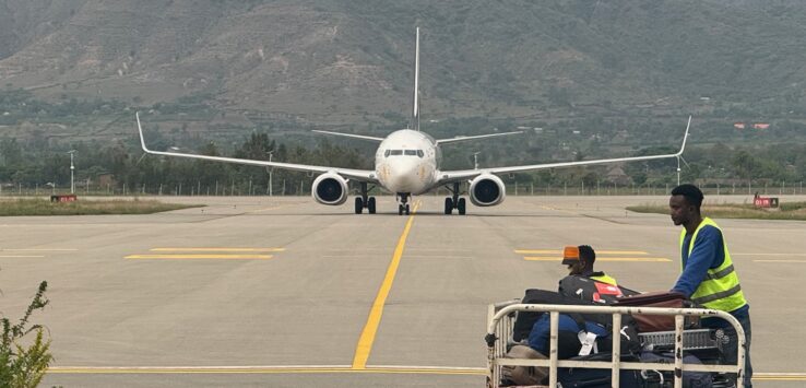 a group of people sitting on a runway with a large white airplane