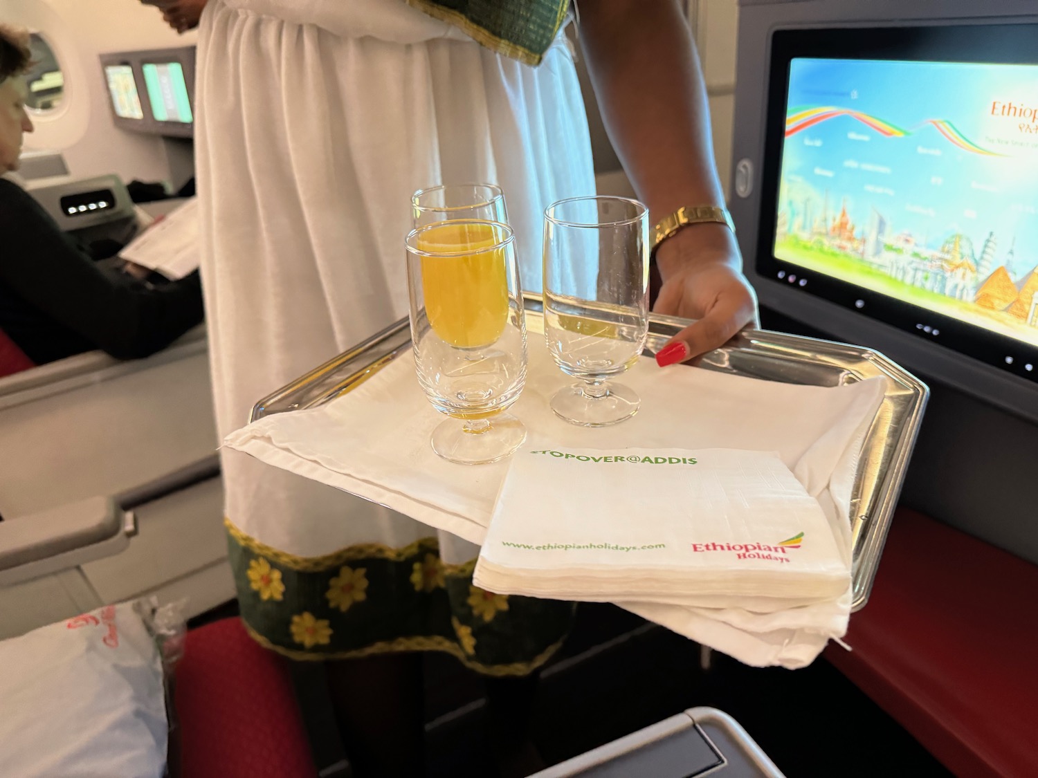 a woman holding a tray with glasses and napkins