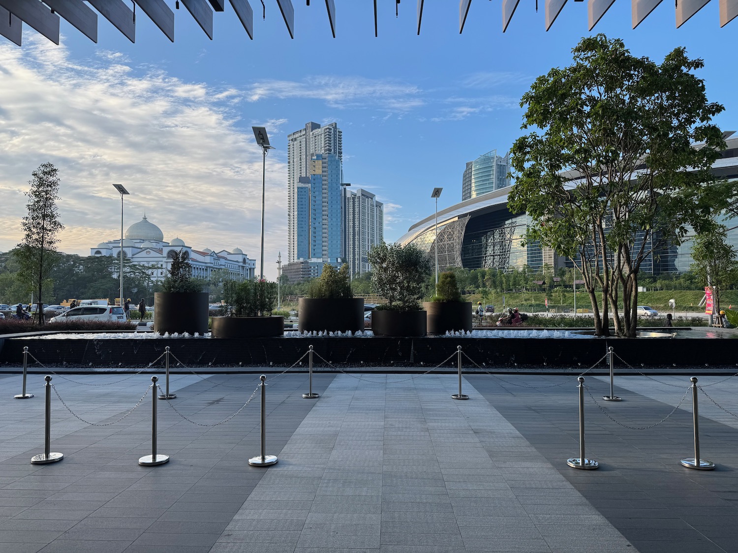 a walkway with a group of trees and a building in the background