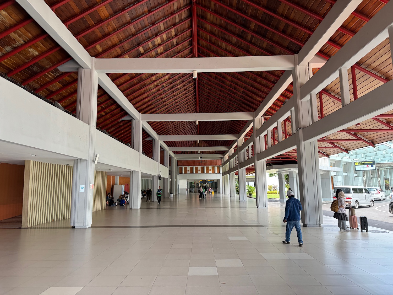 a large white building with red beams and people walking