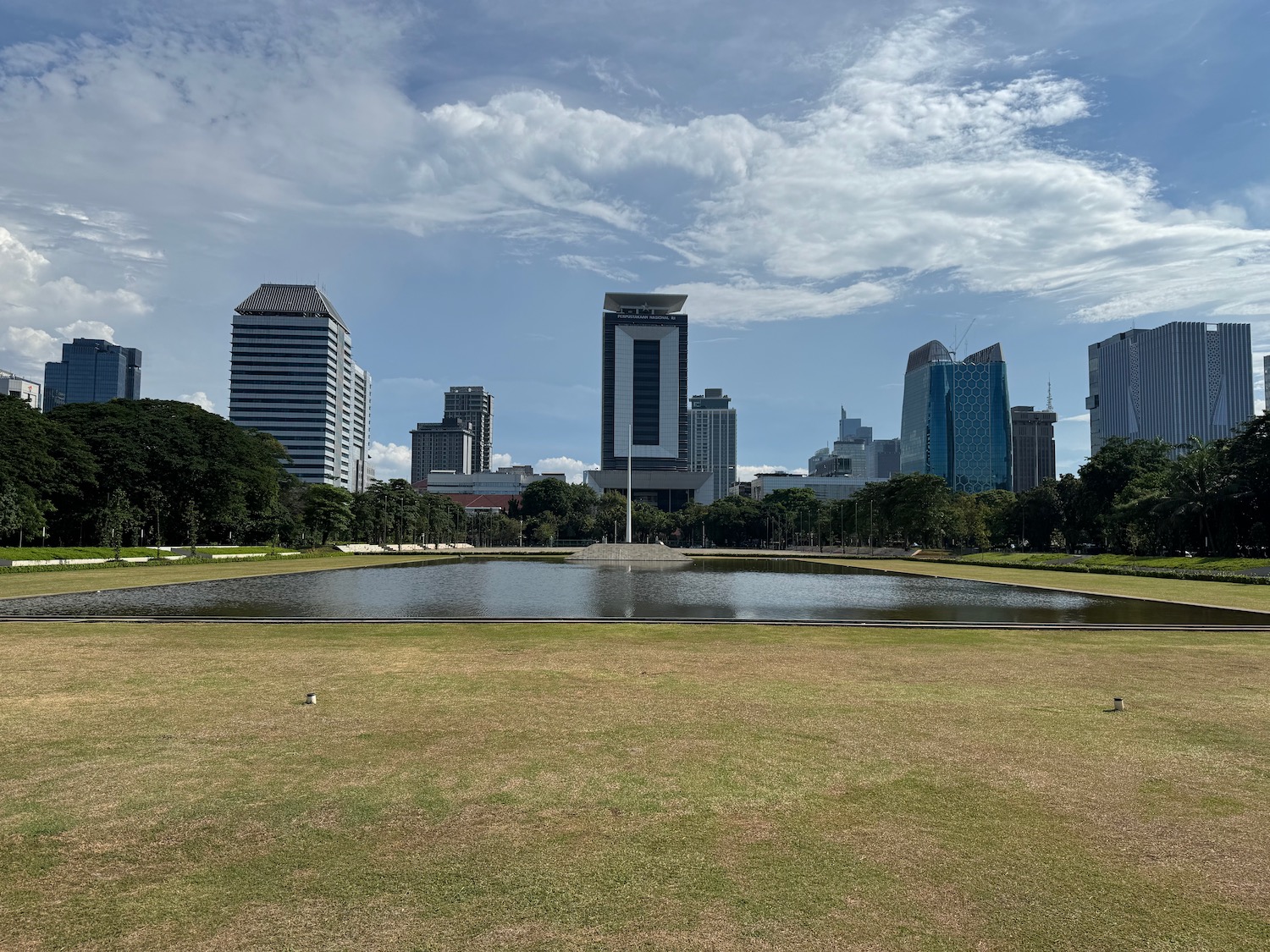 a pond in a park with a large building in the background