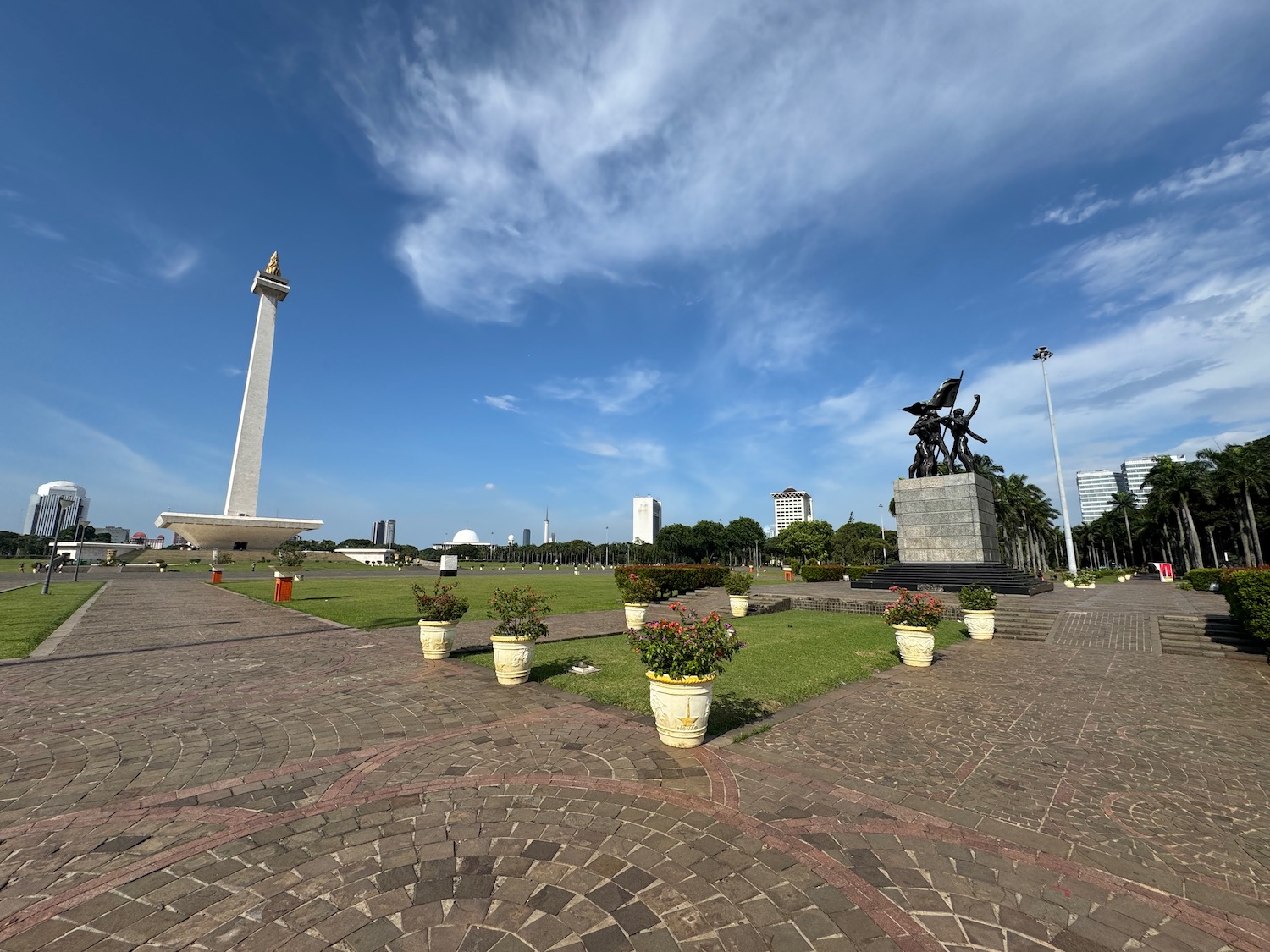 a stone walkway with a monument and a statue in the background