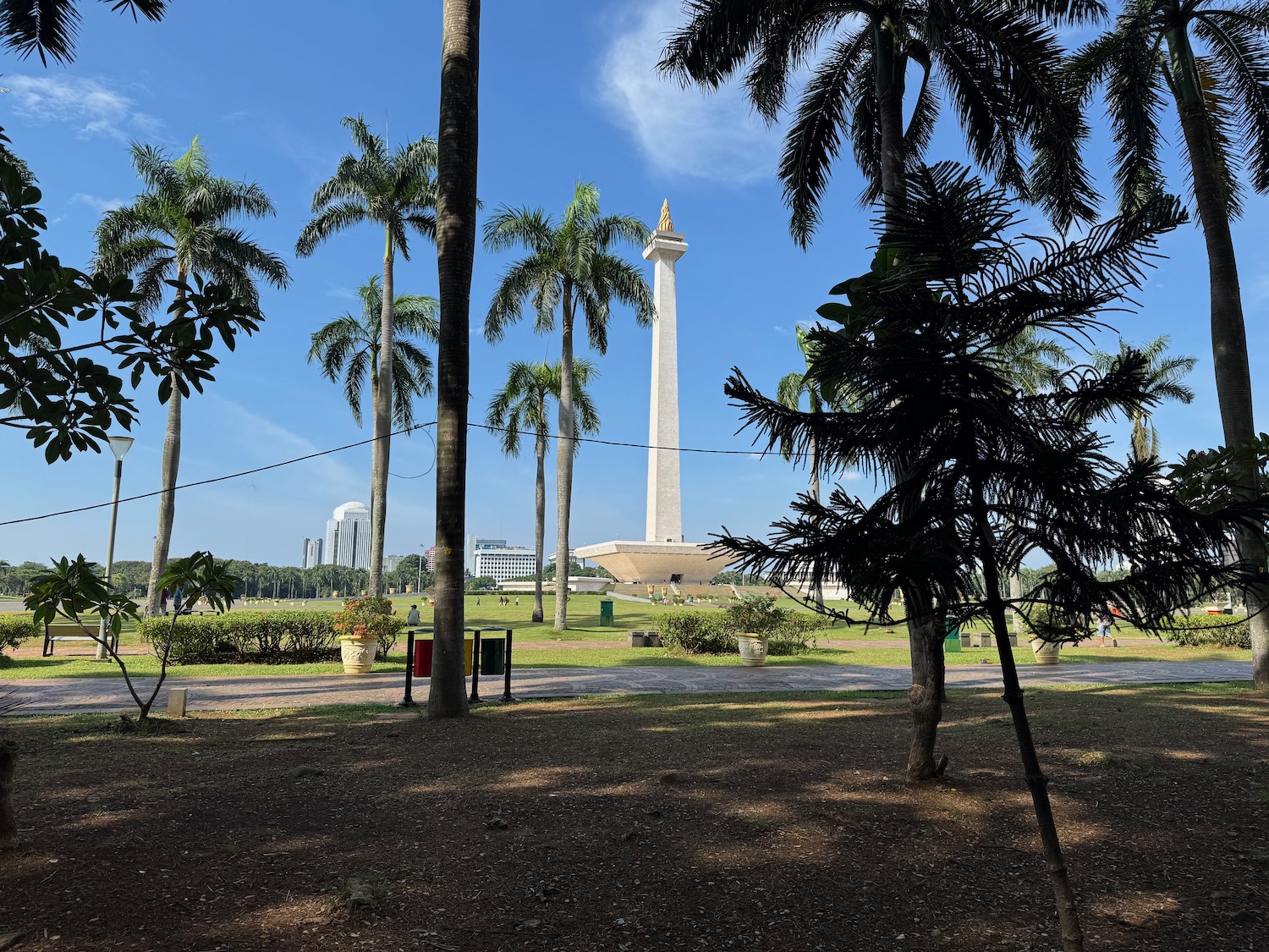 a tall white tower with a gold top and a large circular platform surrounded by palm trees