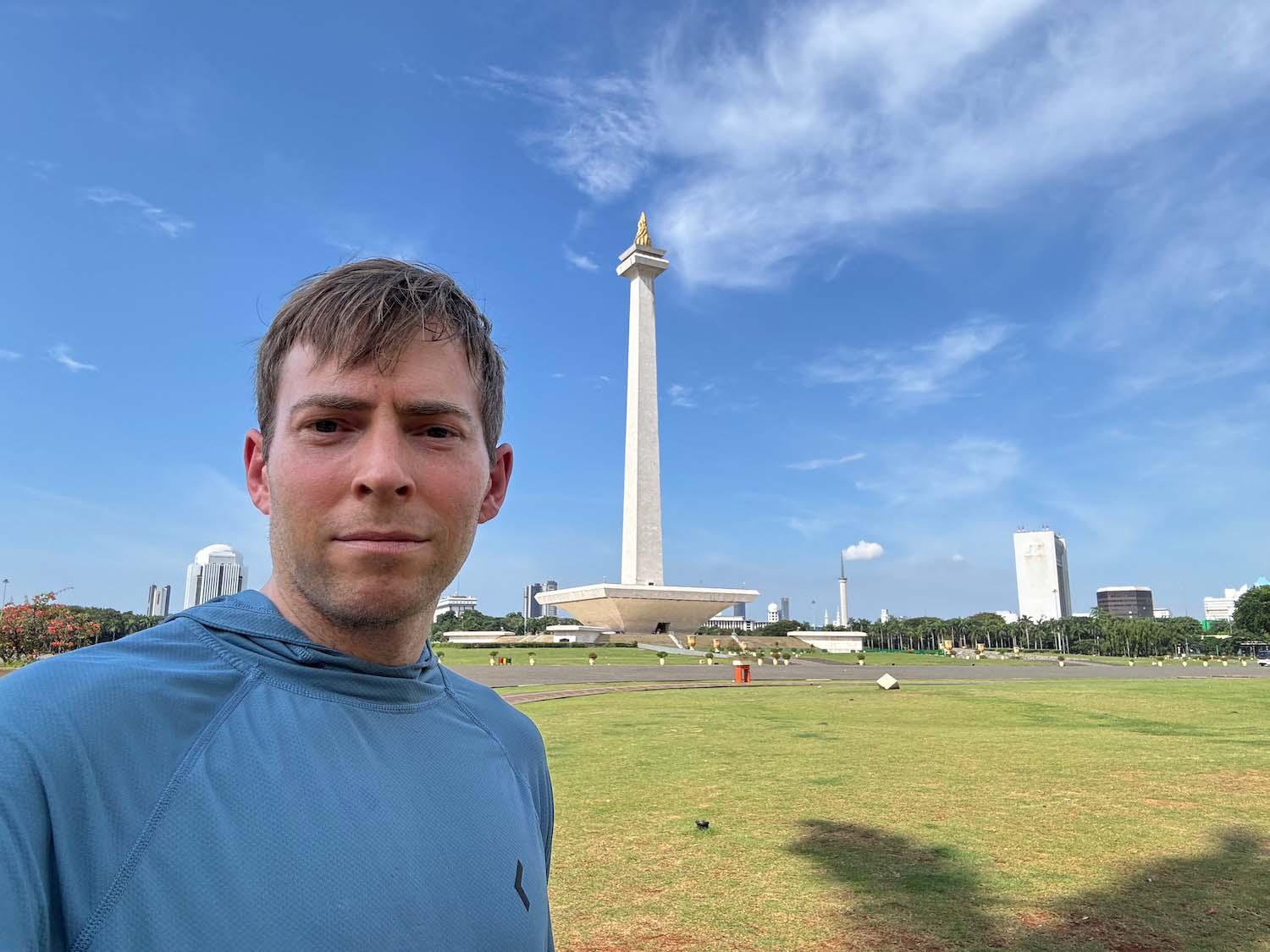 a man taking a selfie in front of a tall white monument