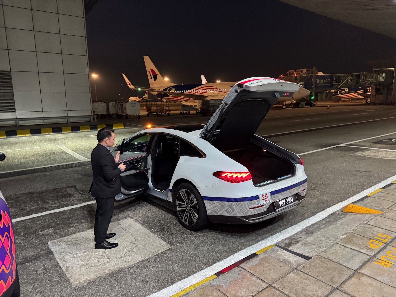 a man in a suit opening the trunk of a car