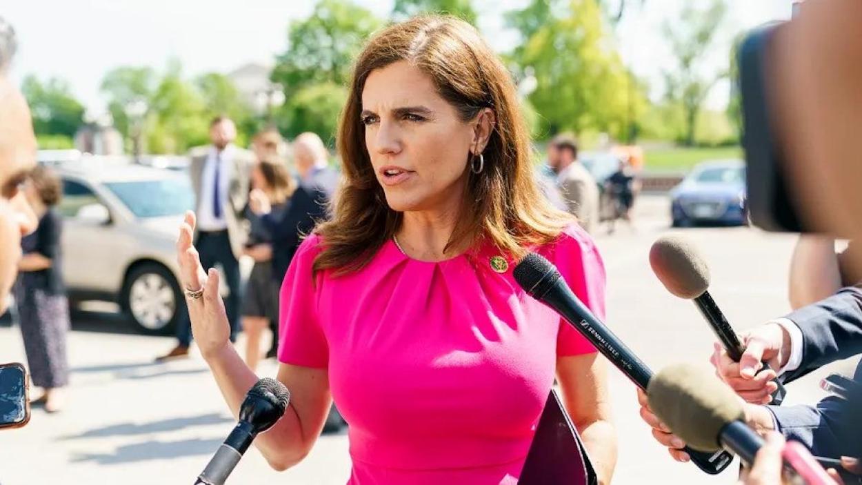 a woman in a pink dress speaking into microphones