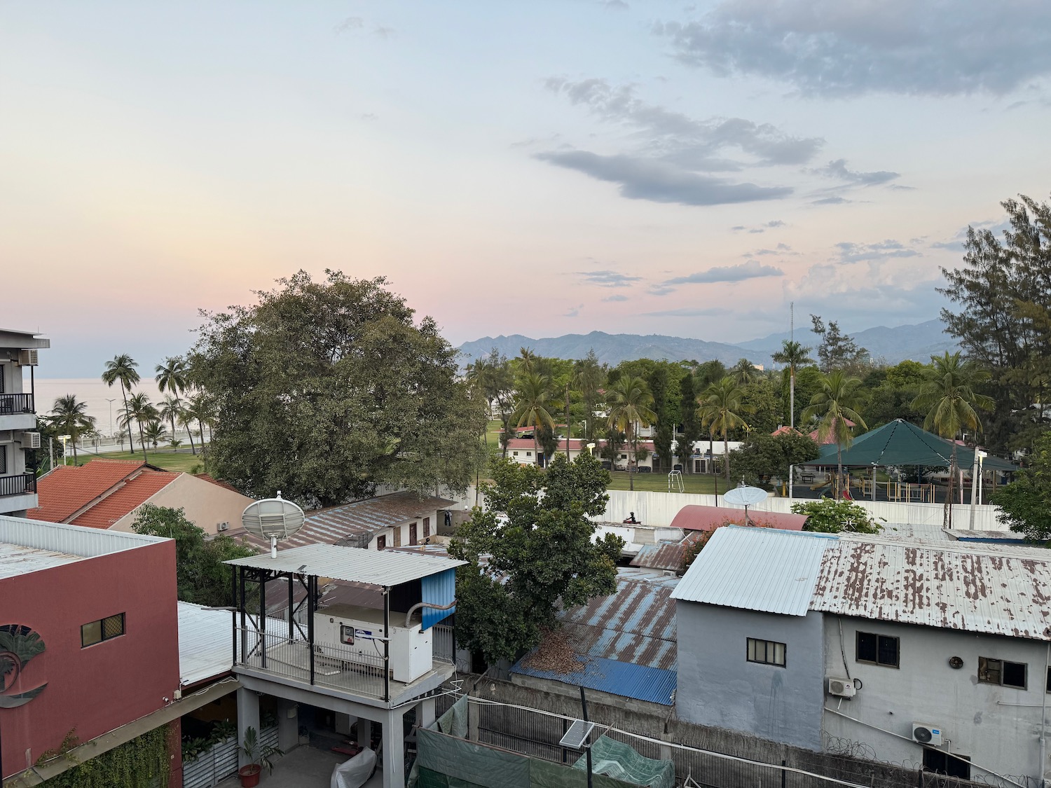 a group of houses with trees and mountains in the background