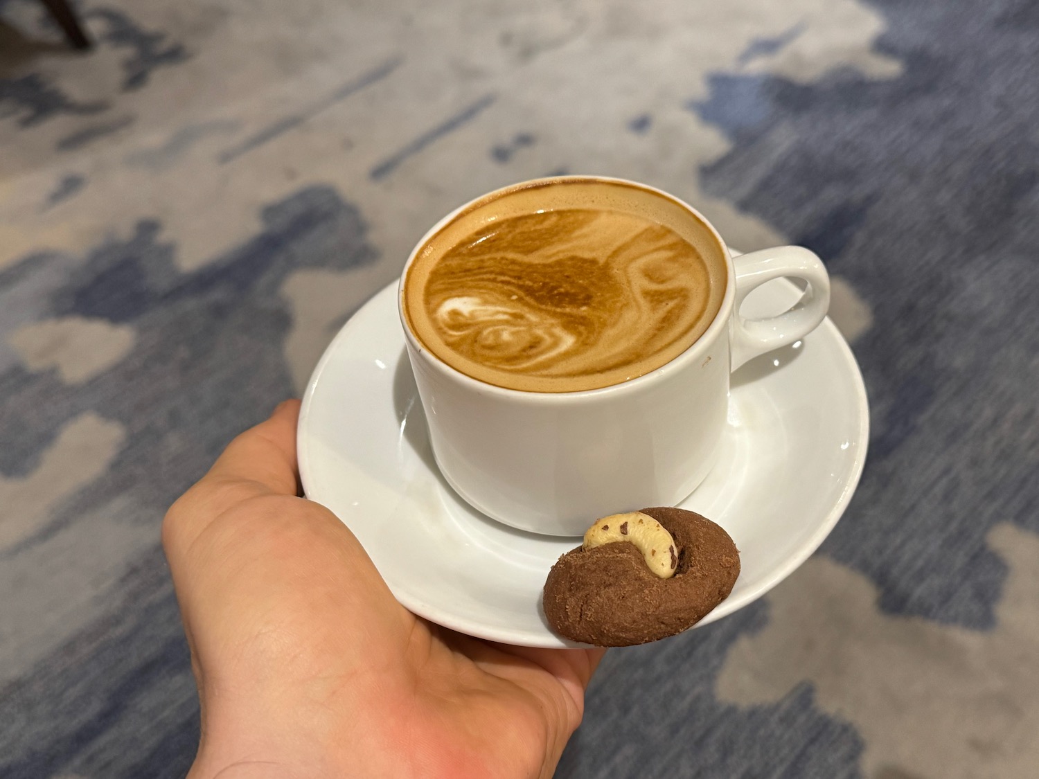 a hand holding a cup of coffee and a cookie
