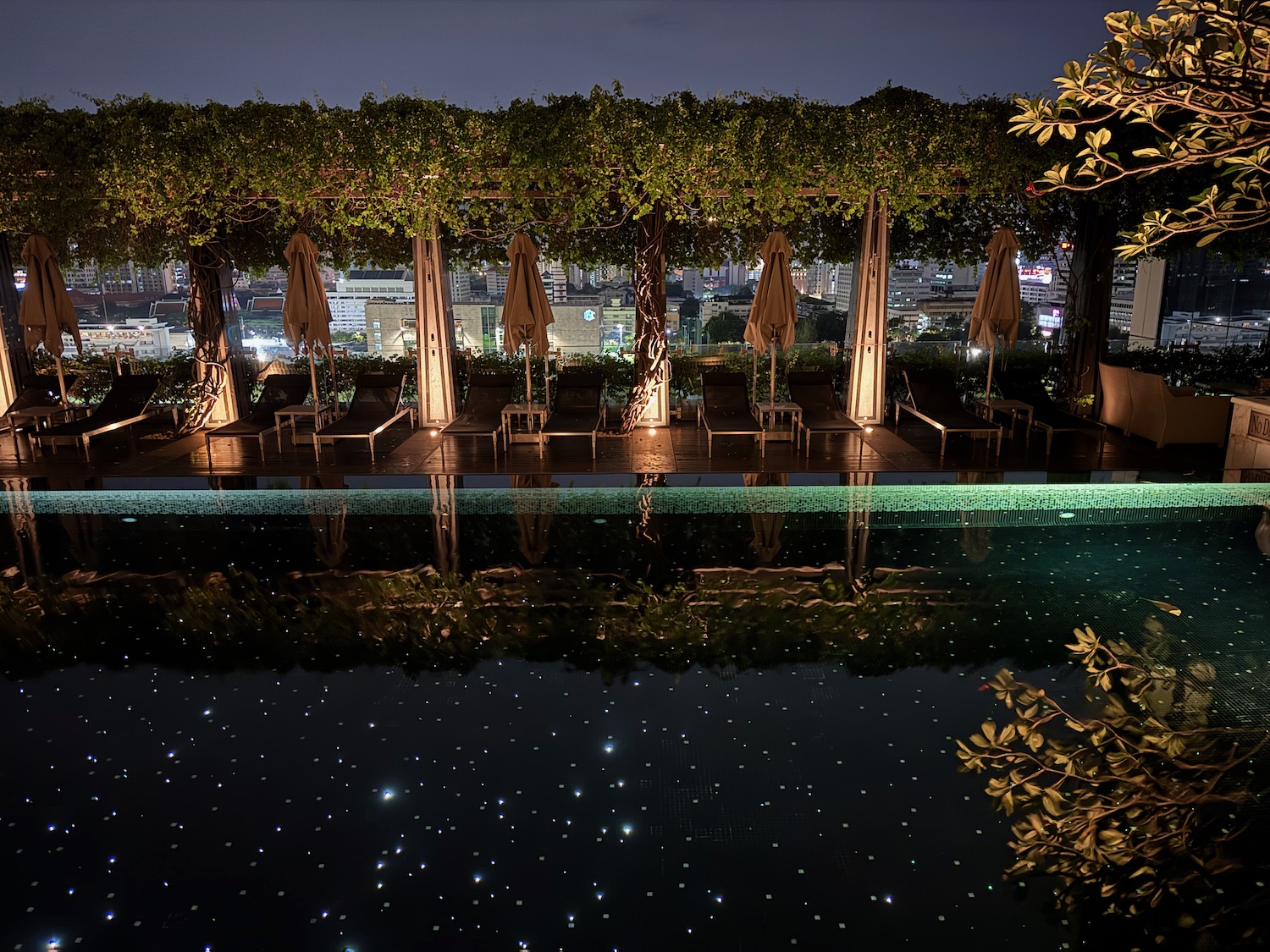 a pool with trees and chairs and umbrellas