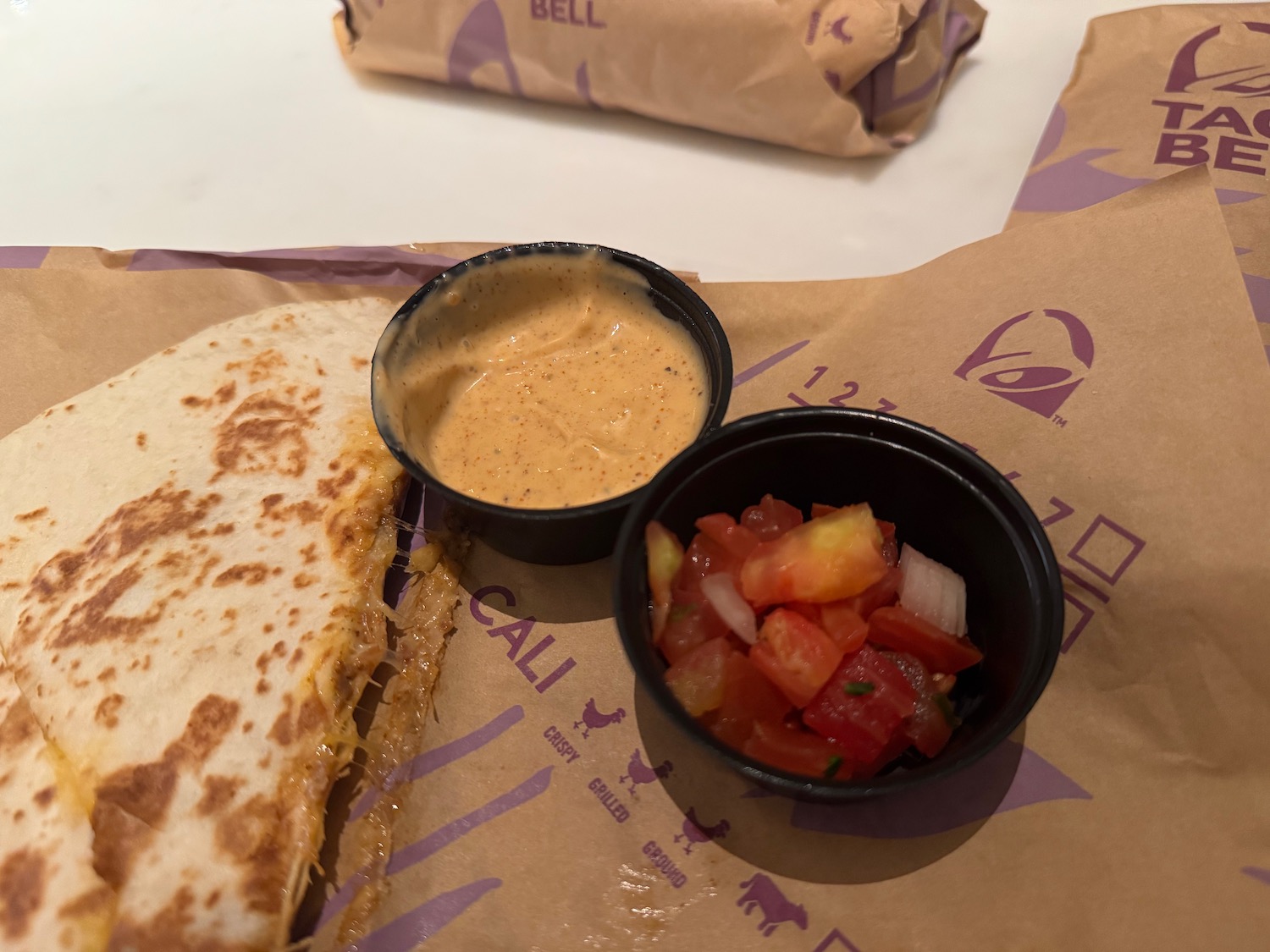 a quesadilla with salsa and sauce on a paper wrapper