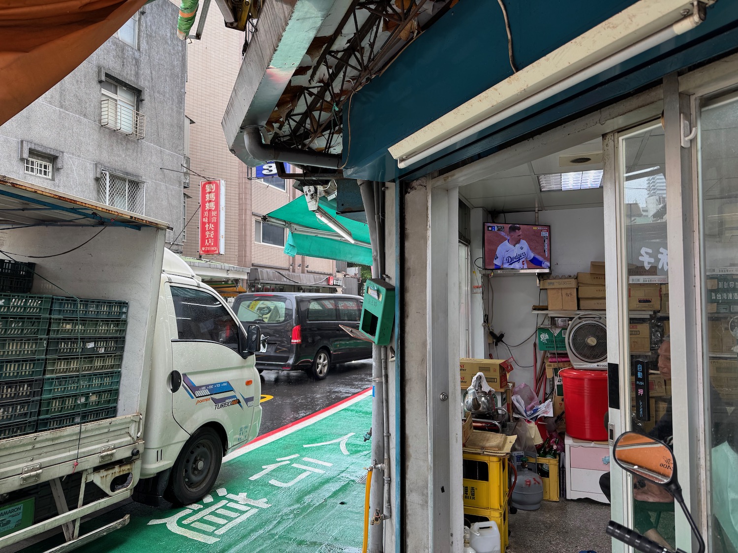 a store with a green area and a few cars parked on the side of the road