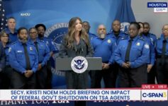 a woman standing at a podium with a group of people behind her