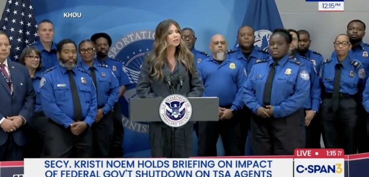 a woman standing at a podium with a group of people behind her