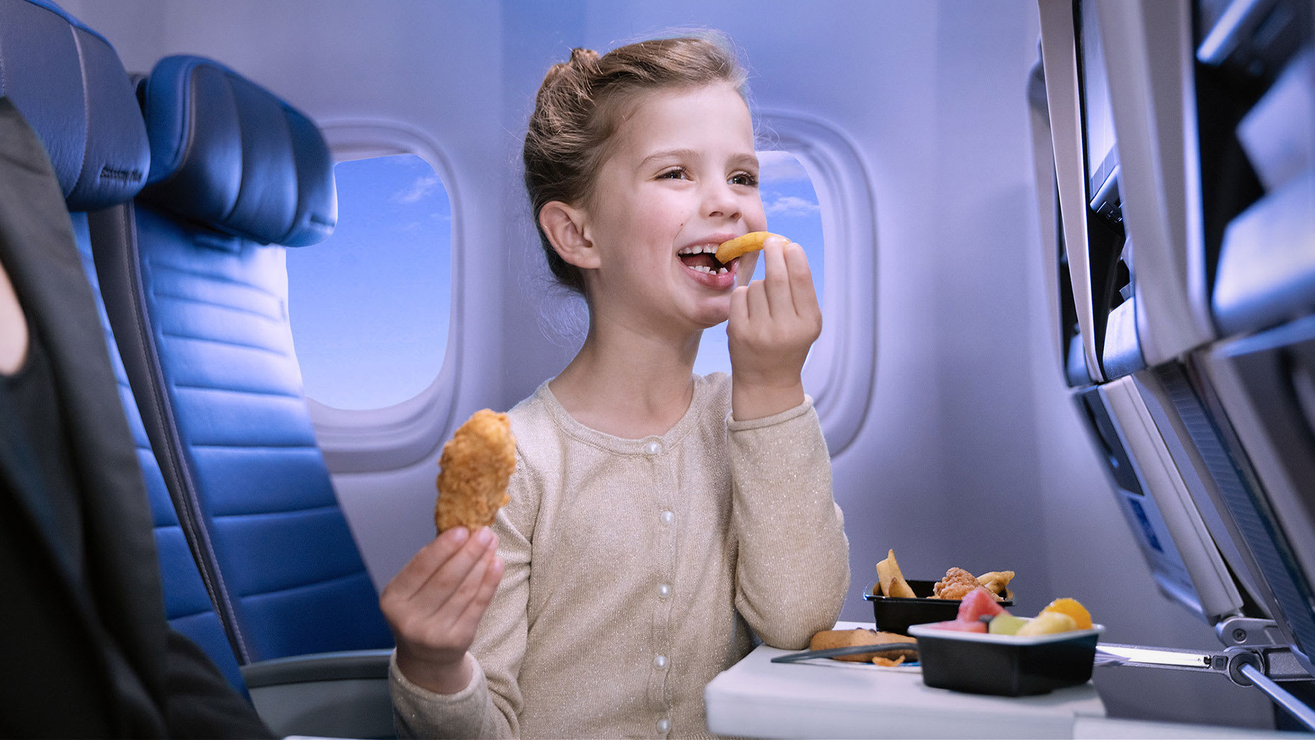 a girl eating food in an airplane