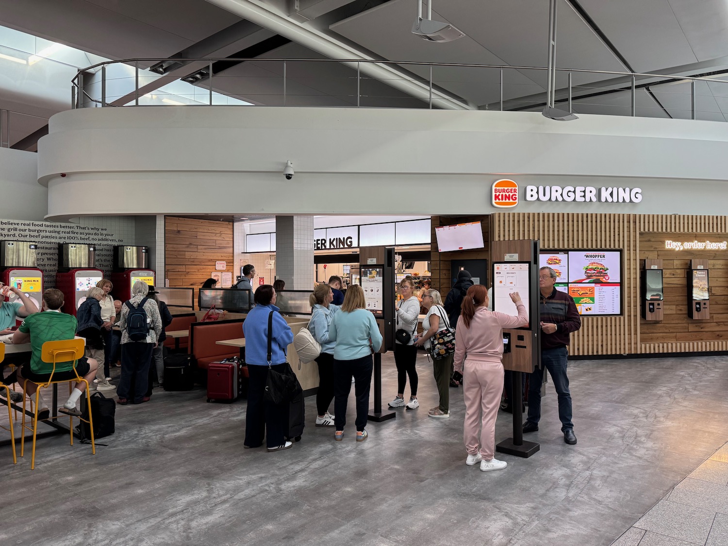 a group of people standing in a line in a food court