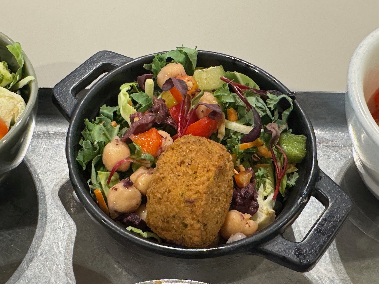 a bowl of salad with a piece of food